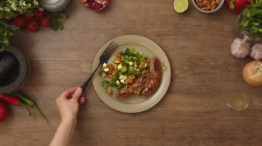 Anonim bir aşçının tabağa çatal, taze sebze salatası ve ahşap masada spagettili kızarmış sosis koymasının en iyi görüntüsü.