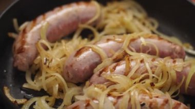 Yakın çekim yüksek açı, gerçek zamanlı anonim kişi sıcak soğan ve ev yapımı sosislerle kızartma tavasına soya sosu ekliyor.