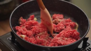 Yüksek açılı, gerçek zamanlı, kızartma tavasında spatulayla kıyma karıştıran isimsiz bir insan.