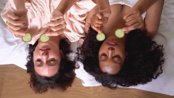 从上面看 年轻的多种族女性躺在白色的毛毯上 眼睛上放着黄瓜片 — 图库视频影像