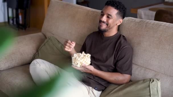 Cheerful African American Male Resting Comfortable Sofa Looking Away Eating — Stock Video