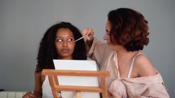 Mujer Joven Con Pelo Corto Sosteniendo Pincel Mientras Pinta Cara — Vídeos de Stock