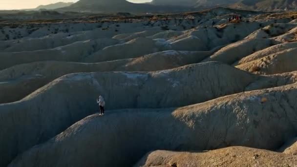 日没時に砂漠で写真を撮りながら荒々しい岩の形成に立っている 認識できない旅行者の周りのドローンビューパン — ストック動画