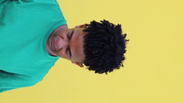 年轻的非洲裔美国男性的画像 留着恐惧的头发 身穿绿色T恤 抬起头来笑着 看着镜头映衬着黄色背景 — 图库视频影像