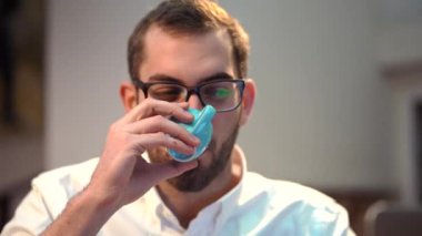 Odaklanmış erkek barista, elinde dizüstü bilgisayarla oturmuş kahve dükkanında çalışırken not alıyor.