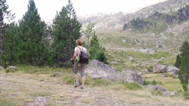 Yetişkin bir kadın, günlük kıyafetlerini giymiş. Yaz mevsiminde, yamaçta yürüme ve taşlı yolda yürüme antrenmanı yapıyor.