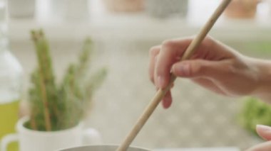 Anonim kadın aşçı spatulayla sıcak makarna karıştırırken ev mutfağında fırında yemek hazırlıyor.