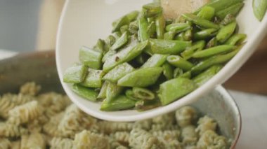 Anonim aşçı haşlanmış yeşil fasulye tavada makarna ve pesto sosu mutfakta öğle yemeği için hazırlandı.