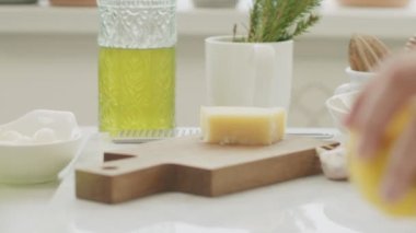 İsimsiz bir kadın mutfakta bıçakla sulu limon kesiyor.