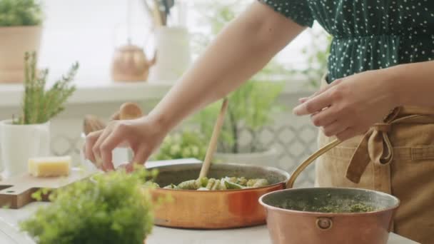 无法辨认的女厨师在平底锅里倒入新鲜的意粉球 配上绿豆酱 — 图库视频影像
