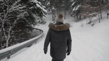 Kışın ormanda boş vakit geçirirken, donmuş yapraksız ağaçların arasında kalın kar tabakasıyla kaplı yolda yürürken tanımlanamayan erkek görüntüsü.