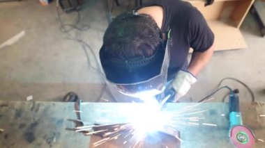 Tanımlanamayan, koruyucu kask takan, atölyedeki tezgahta metal kaynak yapan erkek bir usta.