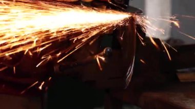 Demir işleme eldivenlerinde isimsiz bir usta demir öğütücüye kelepçelenmiş kıvılcım öğütücü ile.