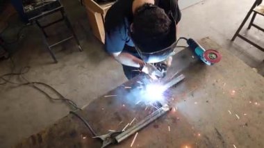 Tanımlanamayan, koruyucu kask takan, atölyedeki tezgahta metal kaynak yapan erkek bir usta.