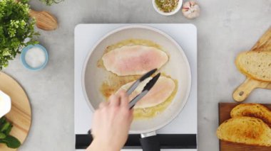 Mutfakta iştah açıcı tost hazırlarken tavada kızarmış tavuk göğsü pişiren yüzsüz aşçının üst görüntüsü.