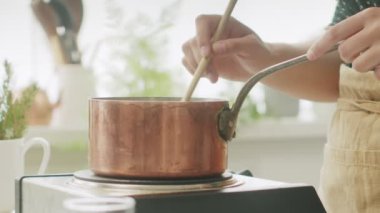 Anonim kadın aşçı spatulayla sıcak makarna karıştırırken ev mutfağında fırında yemek hazırlıyor.