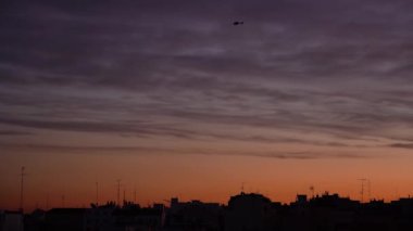 Helikopter siluetinin uzaktan görüntüsü akşam saatlerinde canlı günbatımı gökyüzünün arka planında
