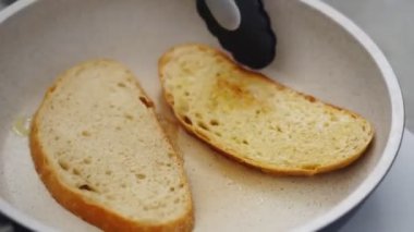 Mutfakta lezzetli tostlar hazırlarken tavada ekmek dilimleri pişirirken tanınmayan birinin maşa kullanmasından.