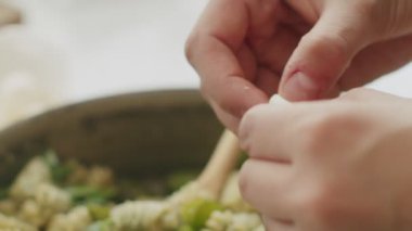 Tanınmayan kadın aşçı taze mozzarella toplarını tavaya dolduruyor yeşil pesto soslu makarna ile
