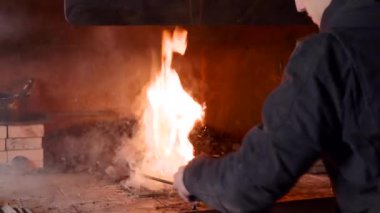 Sıradan giysiler içinde kömür ocağı yangınını sürdüren kimliği belirsiz genç demirci.