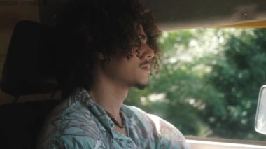 Güneşli bir günde yolculuk sırasında yüzü olmayan erkek karavanın ağır çekimde sürüşü