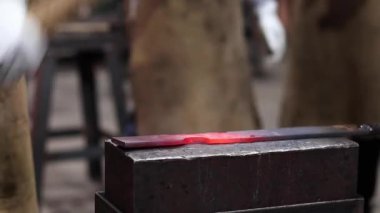 Eldivenli anonim bir zanaatkarın demirci atölyesinde çekici ile sıcak metal detayı yaparken çekilmiş görüntüler.
