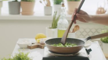 Kimliği belirsiz birinin tavada taze taze fasulye kızartırken gündüz vakti mutfakta sağlıklı bir akşam yemeği hazırlarken görüntüsü.