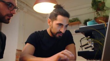 Erkek barmenlerin kafede dizüstü bilgisayarlarıyla oturup iş konularını konuşmaları.