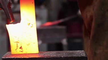 Eldivenli anonim bir zanaatkarın demirci atölyesinde çekici ile sıcak metal detayı yaparken çekilmiş görüntüler.