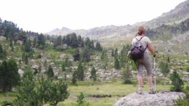 Sırt çantalı, İskandinav yürüyüş direkleri olan sıradan kadın yürüyüşçü, Katalan Pireneleri 'ndeki dağlık Ruda Vadisi' ndeki dağlık tepede dikilirken,