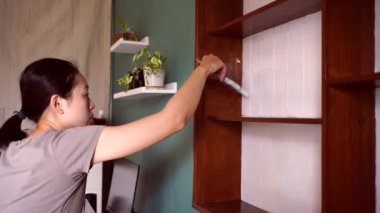 Mobilyaları yenilerken, boyalı fırçalı, tahta rafları beyaz renklerle boyayan etnik bir kadının yan görüntüsü