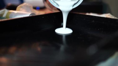 Metal teneke kutudan beyaz boya dökerken daireyi yenilemeye hazırlanan isimsiz kişinin yakın çekimi.