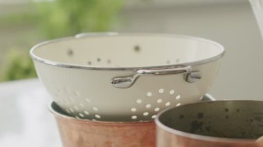 Tanımlanamayan kadın aşçı mutfakta yemek hazırlarken makarna süzmek için süzgecin üzerine pamuk peçete koyuyor.