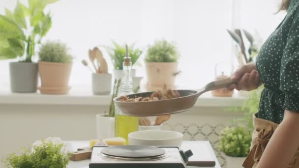 昼間のキッチンでの昼食の準備の間にストーブの鍋で認識できない料理のフライと刺激的なクルミの側面ビュー — ストック動画