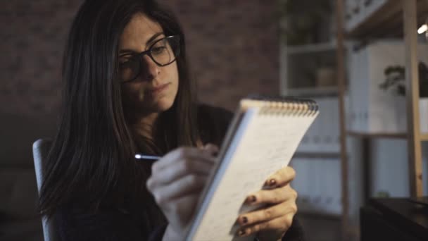 Vista Lateral Compositora Femenina Concentrada Anteojos Tomando Notas Cuaderno Mientras — Vídeos de Stock