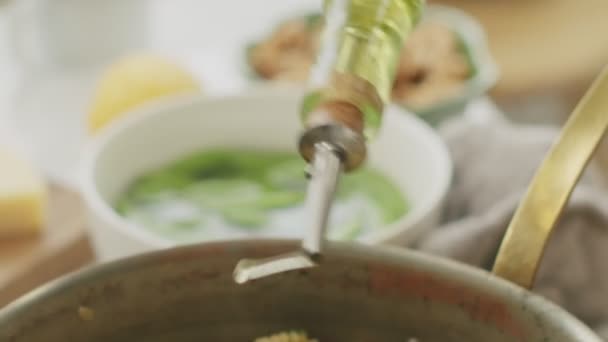 作物の上から 匿名の女性が新鮮なラジオパスタにオリーブオイルを注ぎ キッチンで夕食の準備中にストーブからパンを取る — ストック動画