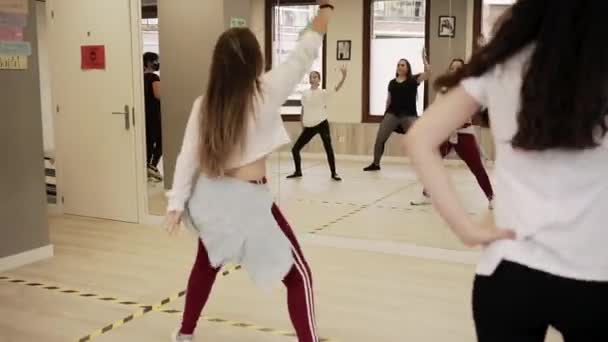 講師とのアクティブなレッスンの間に一緒に広々としたホールで練習しながら ヒップホップダンスの動きをリハーサル若い女性や女の子のグループ — ストック動画