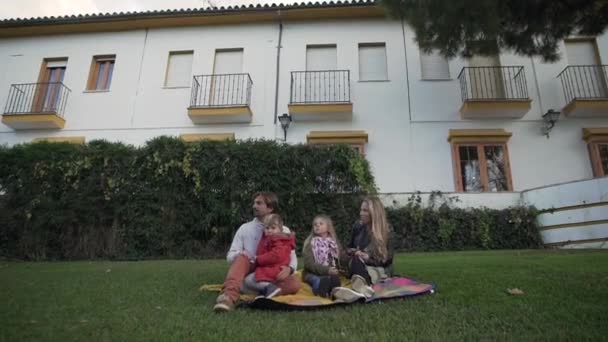 Lykkelig Familie Med Små Børn Smilende Sidder Grøn Græsplæne Nær – Stock-video