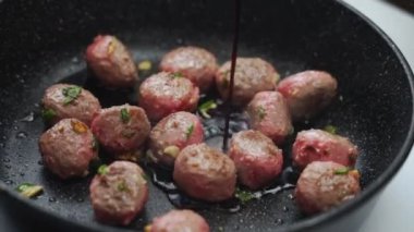 Köfte çeviren, elektrikli fırında kızartan, mutfakta tezgahta yemek pişiren isimsiz bir adam.