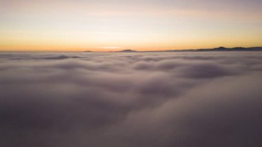 Akşam vakti renkli günbatımında beyaz, kalın ve yumuşak bulutların üzerinde hava manzarası