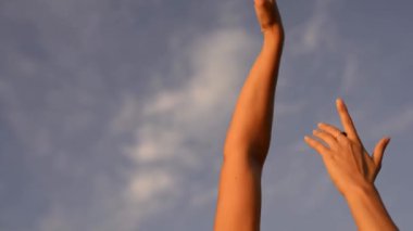 Şehvetli dişi, kollarını kaldırarak bulutlu mavi gökyüzüne karşı dans ediyor.