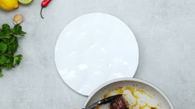 Elinde maşayla, maydanozlu limonlu sarımsak ve biberli kırmızı biberli beyaz seramik tabağa kızarmış köfte koyan...