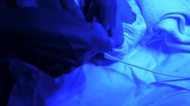 Yoğun bakımda bebek inkübatöründe, hastanede fototerapi için ultraviyole altında yatan küçük ayaklı hasta bir bebeği tutan yukarıdaki insanlardan.