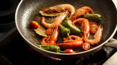 Mutfakta deniz ürünleri yemeği hazırlarken tavada karides karıştıran isimsiz bir aşçının yakın plan fotoğrafı.