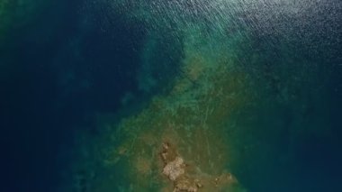 Üst manzara, Isola Rossa 'da bulunan mavi denize yakın yeşil ağaçlarla kaplı engebeli kayalık uçurumları yakınlaştırır.