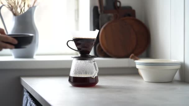 現代のキッチンのテーブルの上に置かれたガラス鍋に紙フィルターから滴り落ちる熱い蒸気のある醸造コーヒー — ストック動画