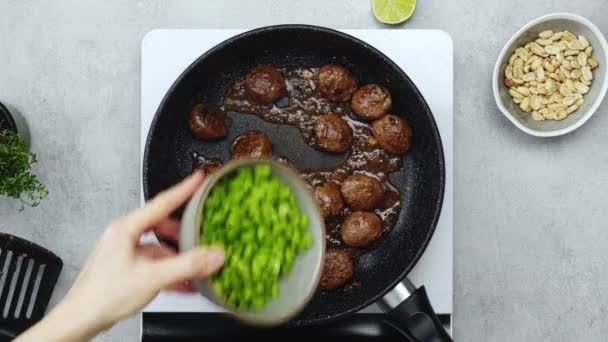ポータブルクッカーの鍋にフライパンに緑豆を追加する顔のない女性料理のリアルタイムトップビュー — ストック動画