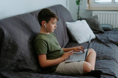 Ciddi küçük çocuk öksürüğünde bacak bacak üstüne atmış ve dizüstü bilgisayarında daktilo yazıyor.