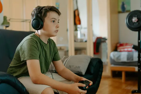 Geconcentreerd Jongetje Casual Kleding Zittend Bank Met Gekruiste Benen Videospel — Stockfoto