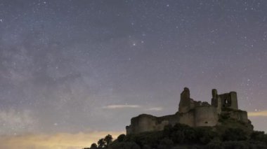 İspanya 'nın Cuenca kentinin kırsal kesiminde yıldızlı gökyüzüne bakan Almenara Şatosu ve yapraksız ağacın hızlandırılmış görüntüsü.